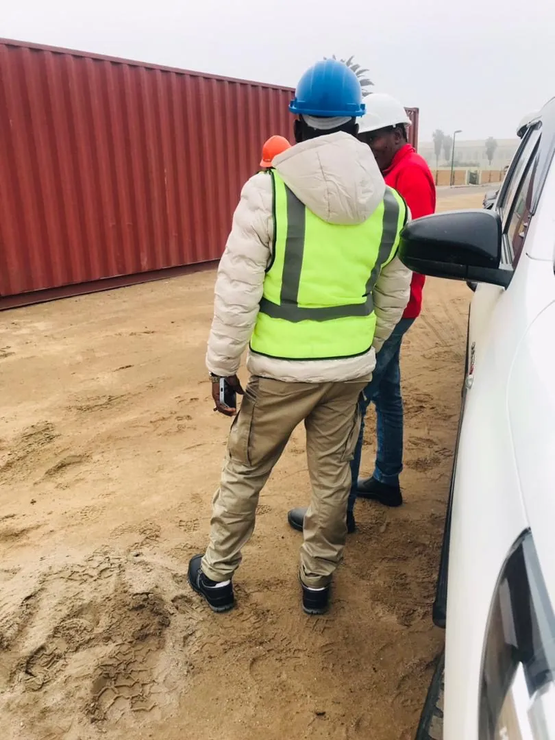 Crew beside a red shipping container at a work site